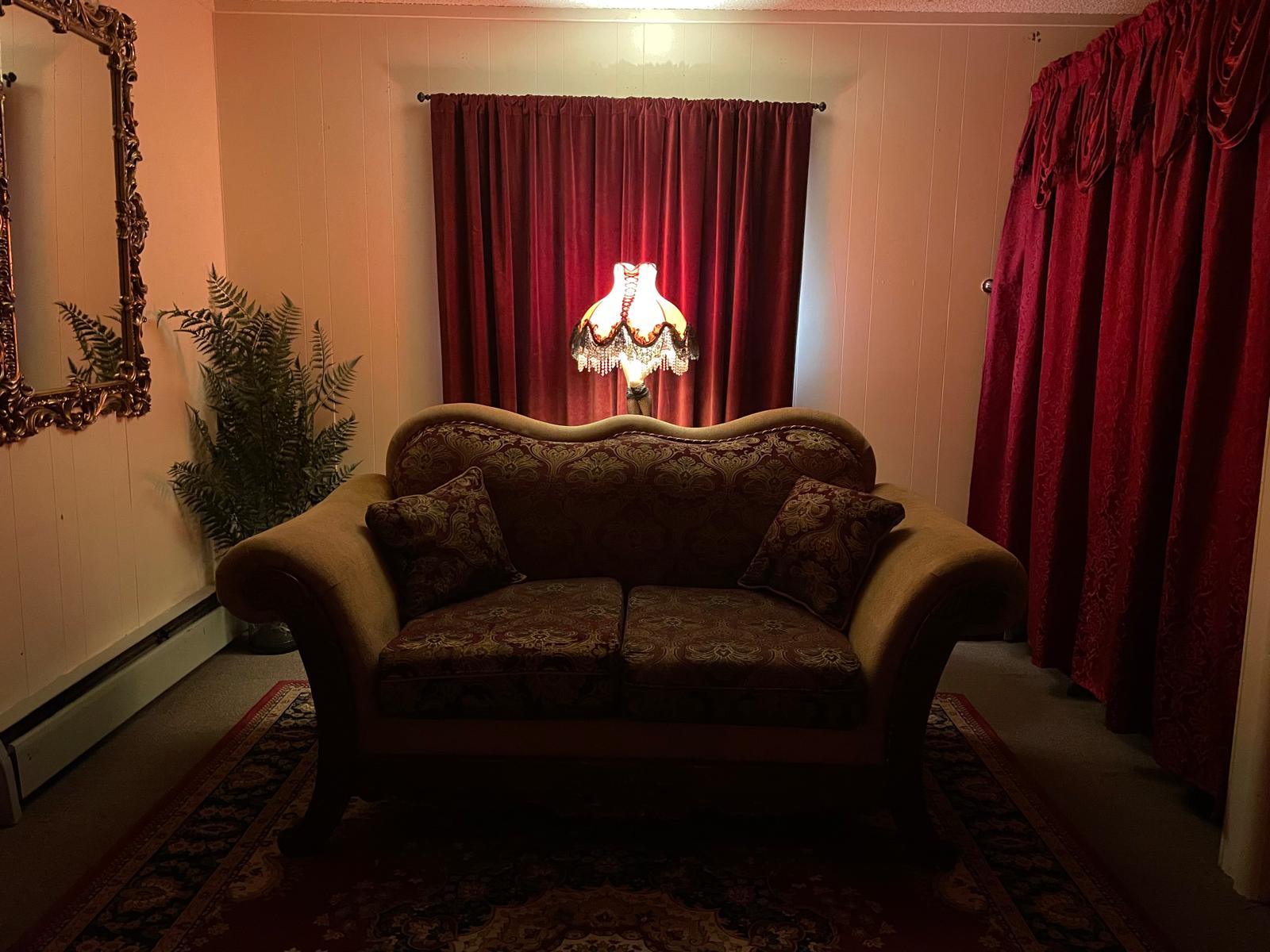 Luxuriously decorated private room with patterned bedding, ornate lamps, mirrors, and atmospheric purple lighting