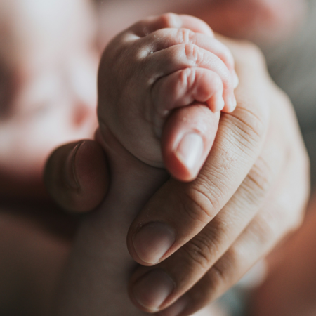 Hand eines Mannes hält Hand eines Babys