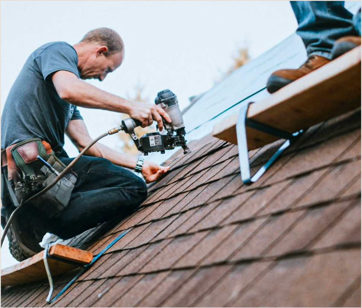 Contractor nailing shingles on a roof