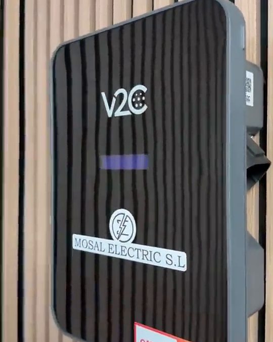 Cargador V2C Trydan negro montado en una pared de listones de madera