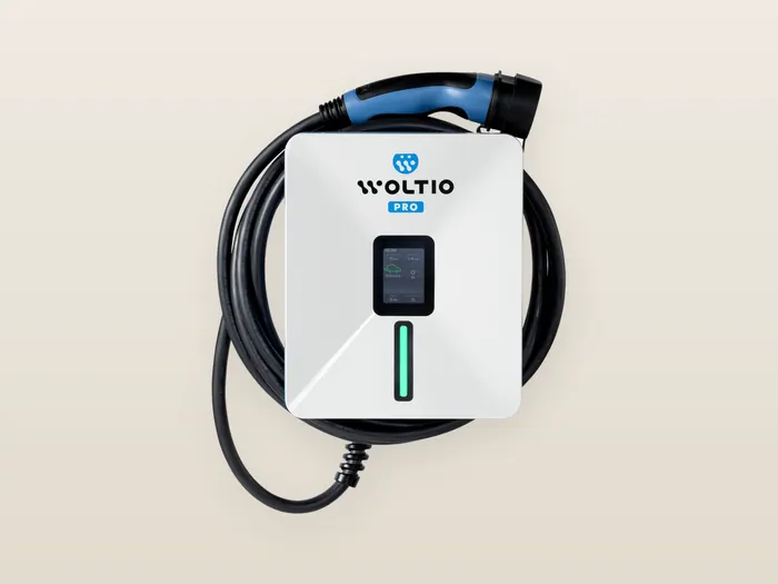 Cargador Woltio PRO blanco, con pantalla a color y franja de luz verde, y su manguera tipo 2 enrollada alrededor