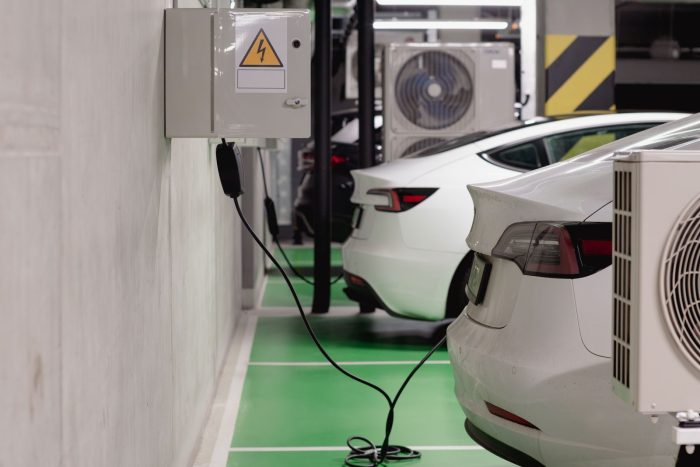 Coches eléctricos cargando en un garaje subterráneo con cajas de protección en la pared