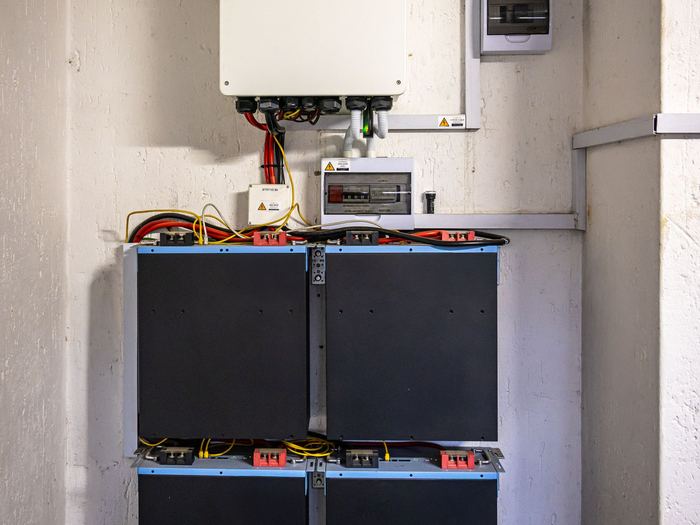 Inversor híbrido y baterías de litio instalados en la pared de un cuarto técnico