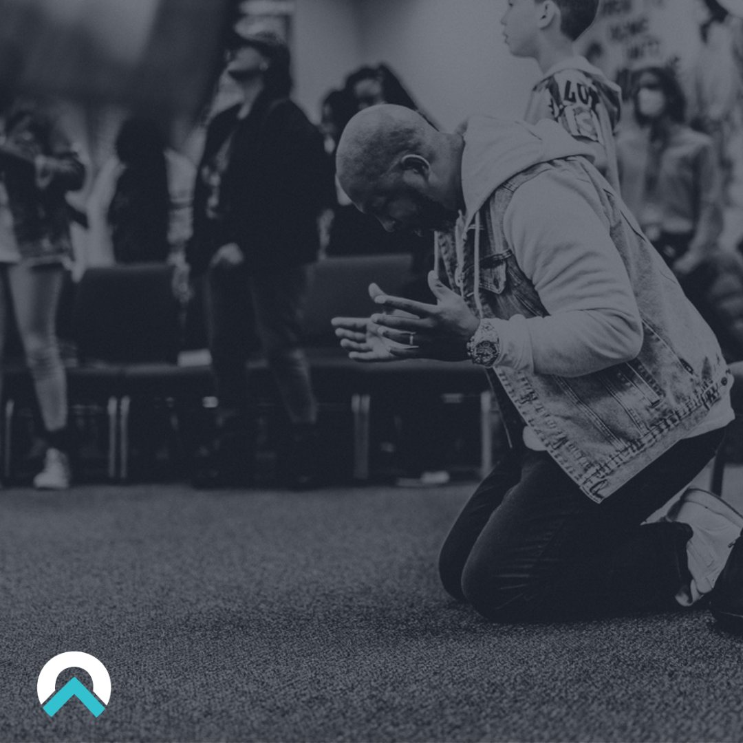 A man kneeling in prayer during worship