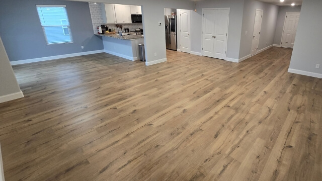 Wood-look laminate flooring installed in an open Raleigh NC living room and kitchen