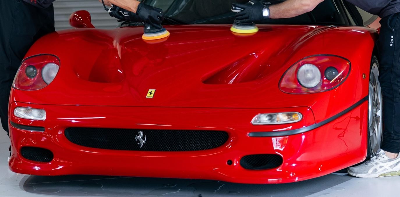 Machine polishing the hood of a red Ferrari at Premier Detailing NJ