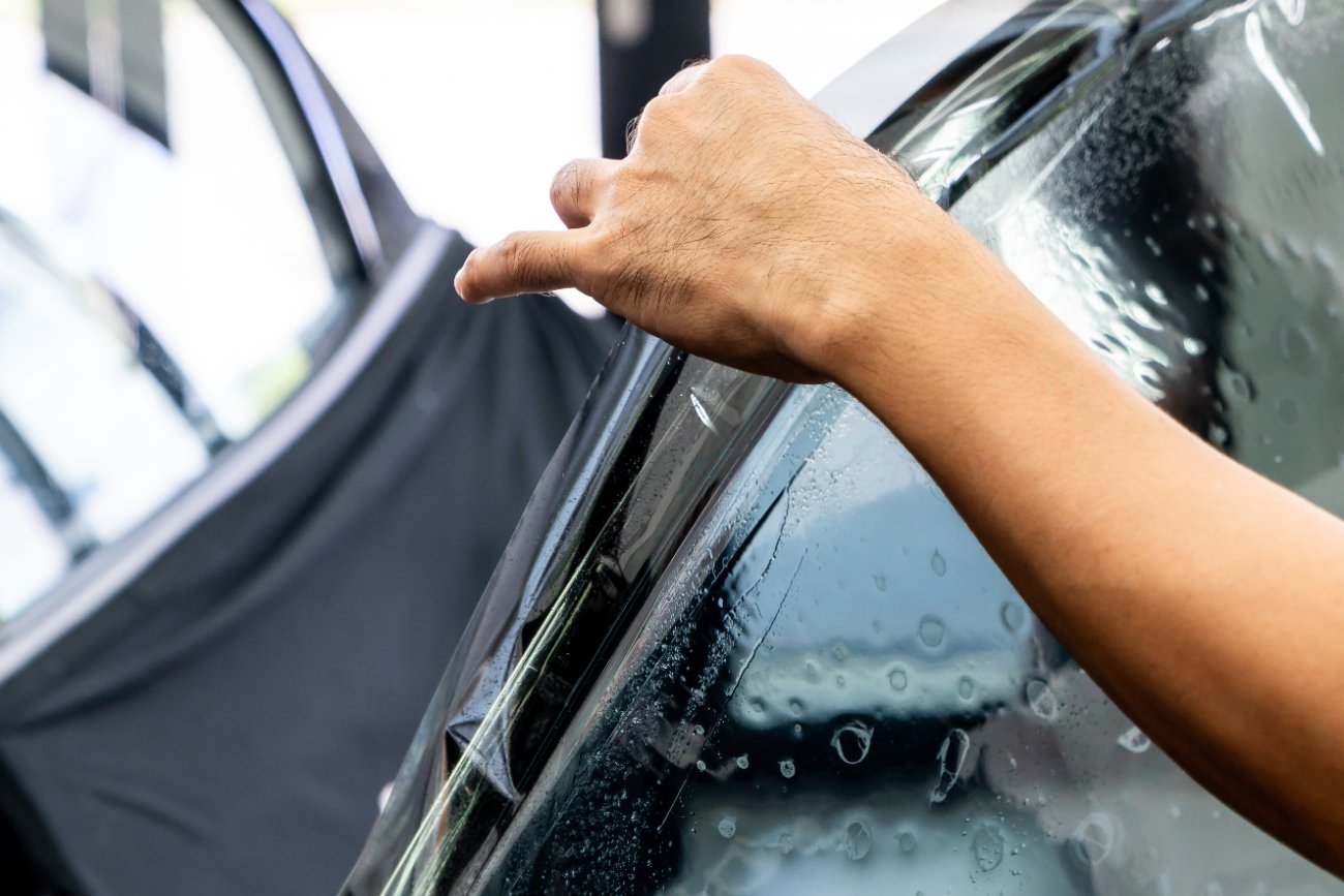Technician applying ceramic window film to a car window
