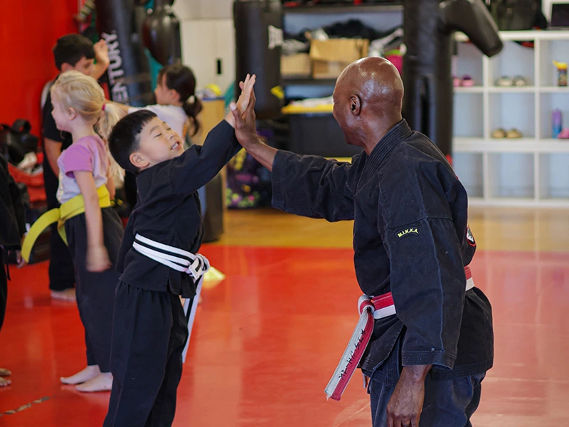 Preschool student high-fiving Sigung James during Preschool Martial Arts class at James Martial Arts Academy in El Cajon