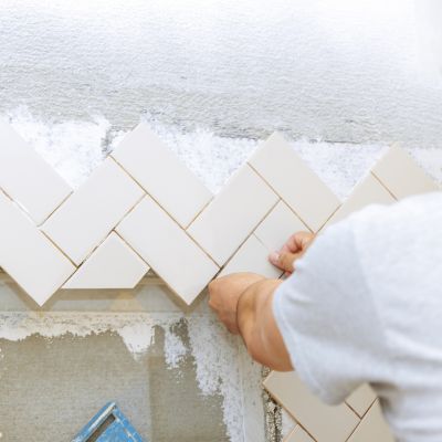 Contractor installing beige tiles in a herringbone pattern