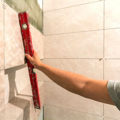 Contractor using a level to ensure even placement of wall tiles