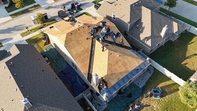 Roofers replacing shingles and underlayment on a large-scale project. 