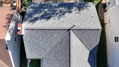 Aerial view of a roofing crew replacing shingles and plywood on a home.