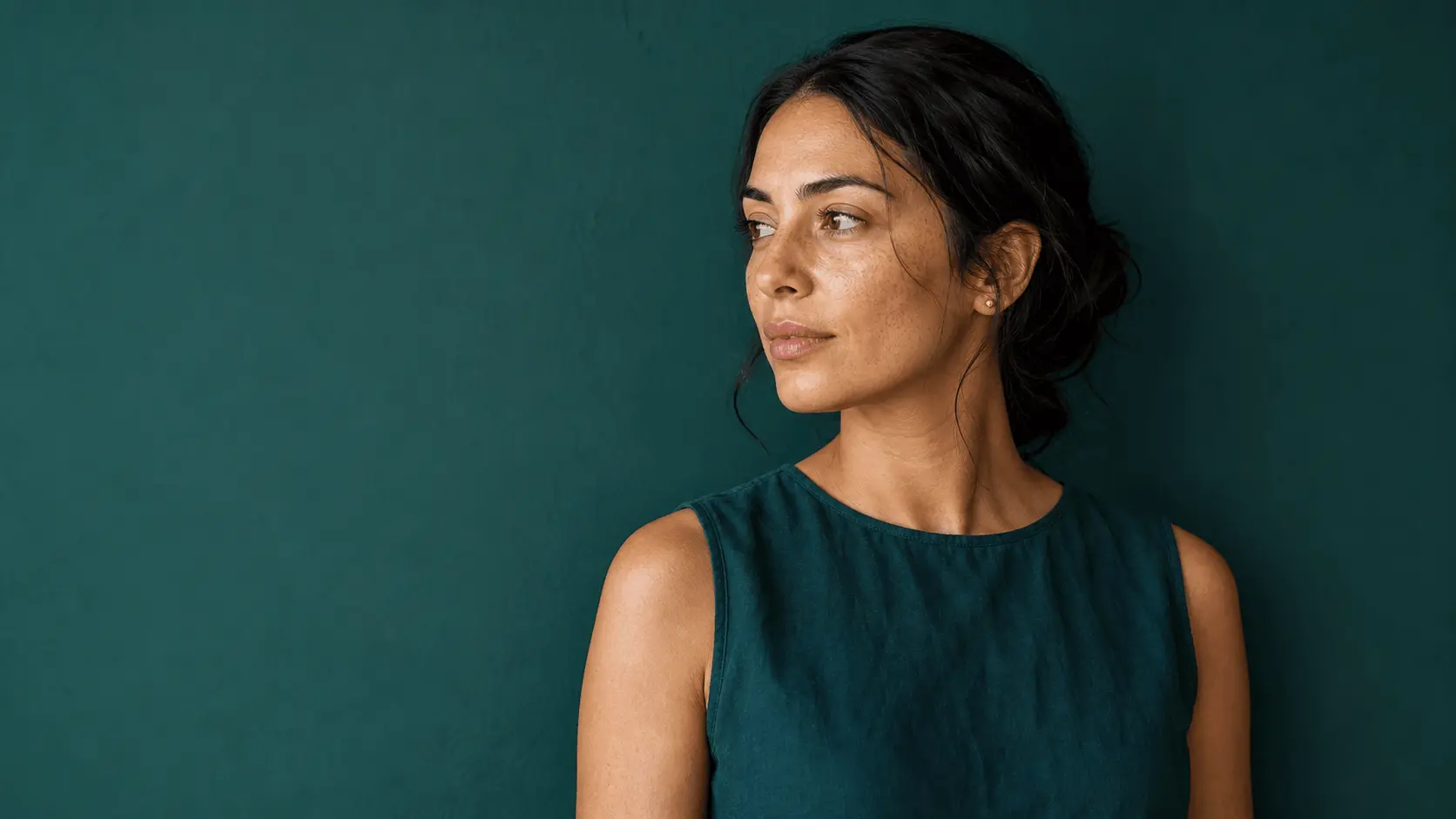 Portrait d’une femme au regard calme, sur fond vert profond