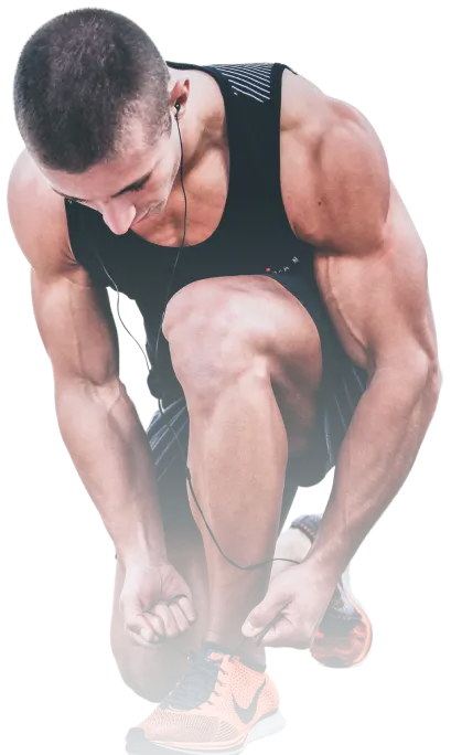 Man in athletic wear tying a shoelace on his bright orange running shoes, with earphones in his ears, looking down outside the Red Fitness Lounge gym.