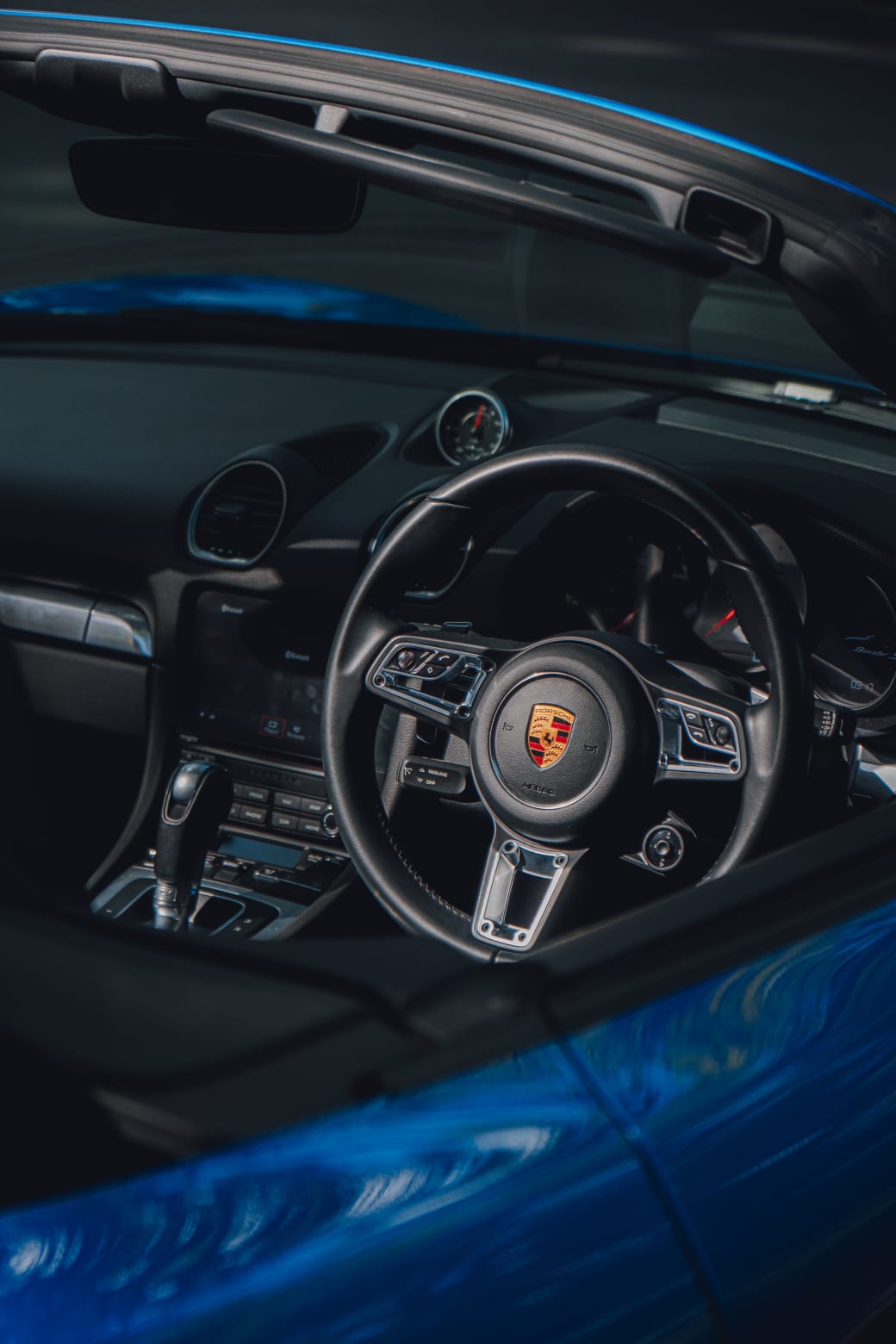 Interior cockpit view of the Porsche Boxster 718 S steering wheel and dashboard.