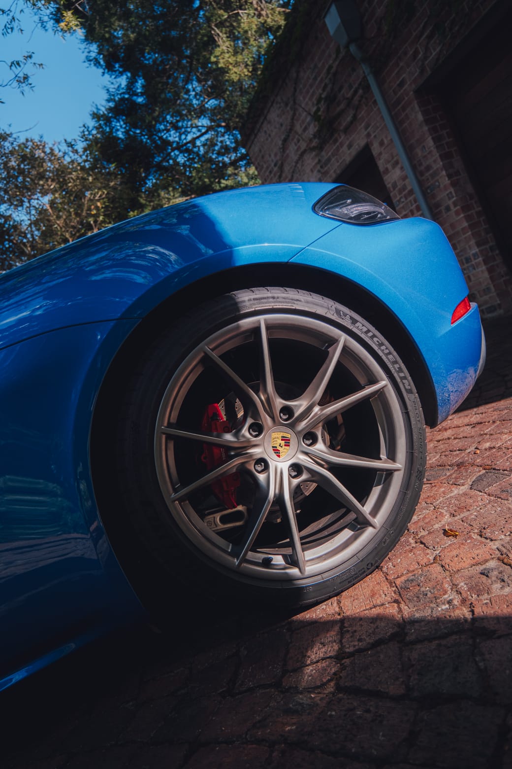 Close-up of the blue Porsche Boxster 718 S front wheel and fender detail.