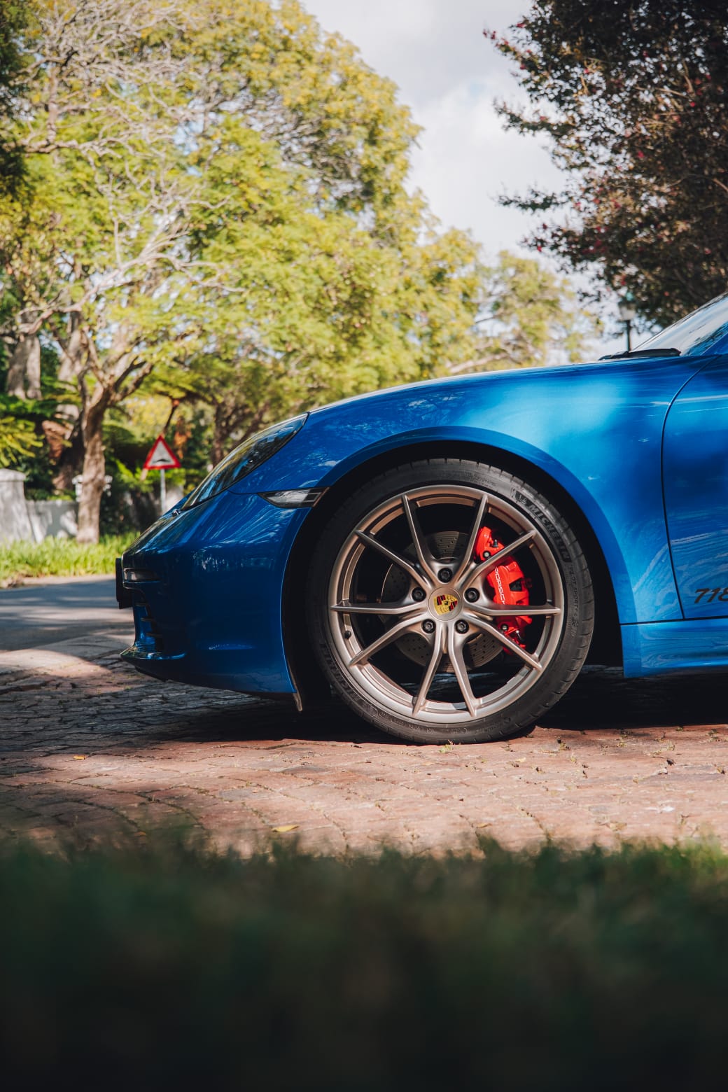 Close-up of the front wheel and brake on the blue Porsche Boxster 718 S.