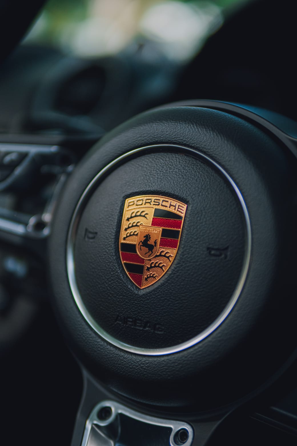 Close-up of the Porsche crest on the steering wheel inside the car.