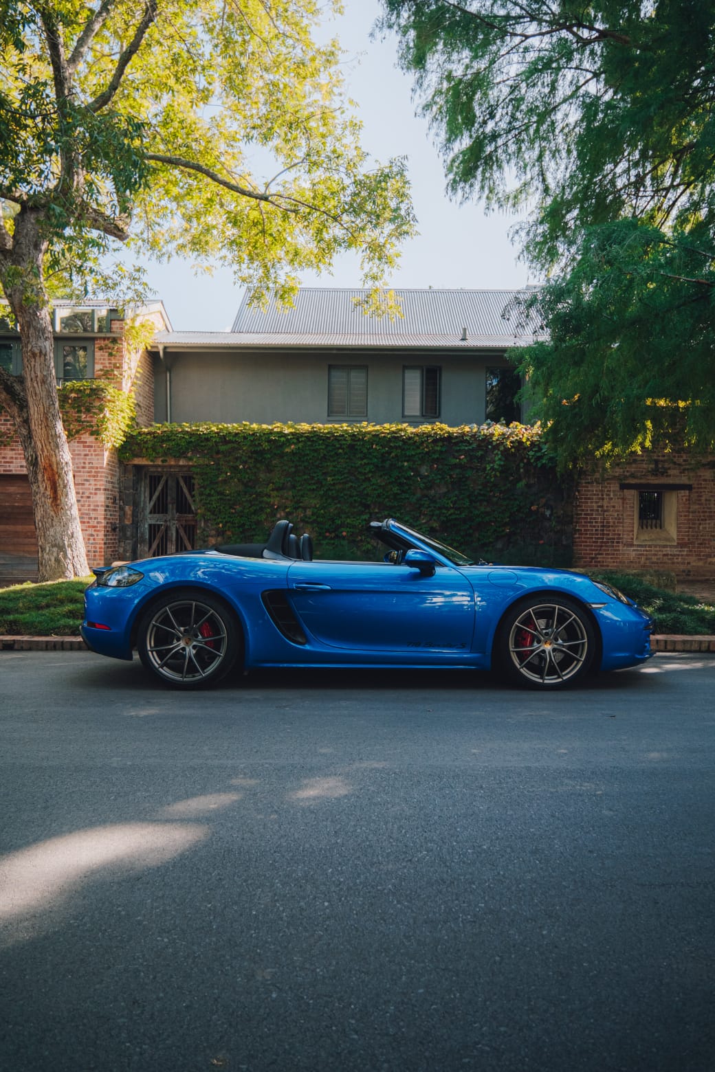 Side profile of the blue 2017 Porsche Boxster 718 S parked outdoors.