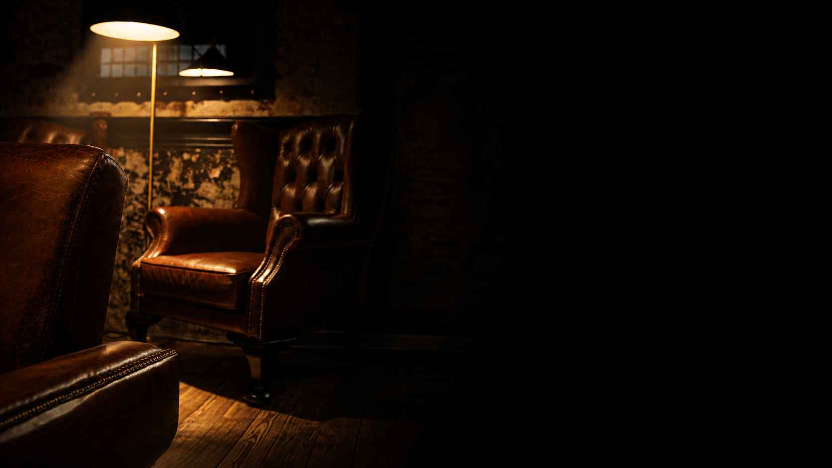 Luxury leather lounge chairs with warm amber lighting fading into black on the right.