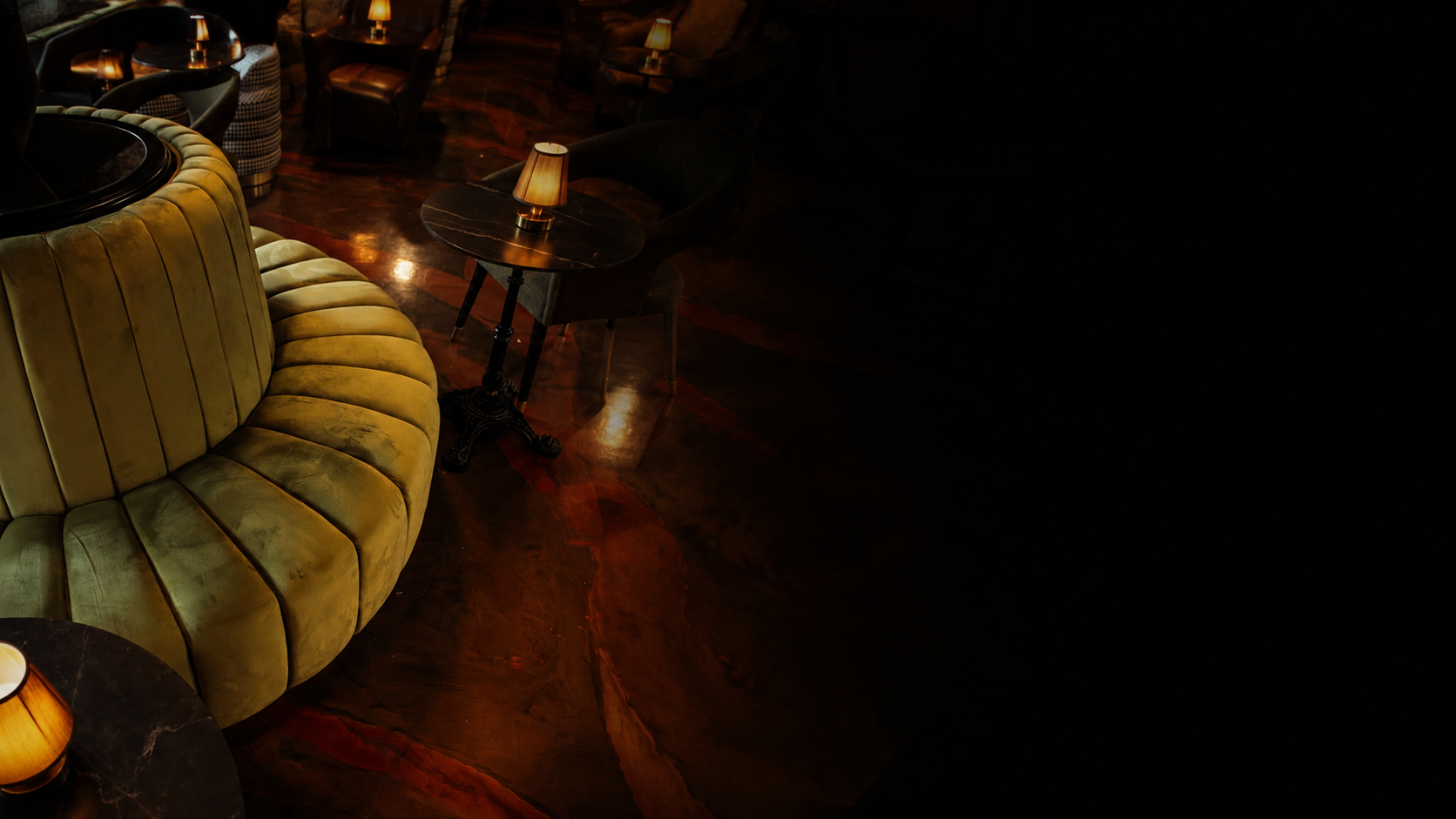 Luxury lounge seating with warm lighting fading into black on the right.