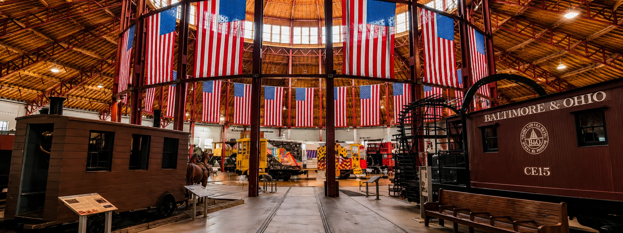 B&O Railroad Museum roundhouse interior in Baltimore, Maryland with historic trains and American flags.