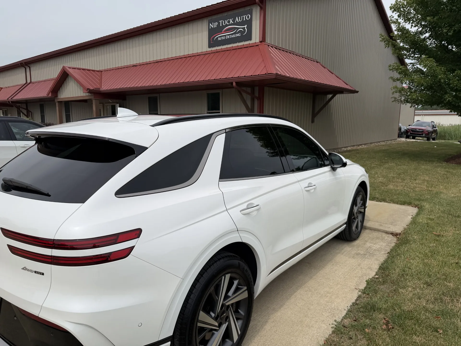 Finished white vehicle with dark tinted windows outside Nip Tuck Auto