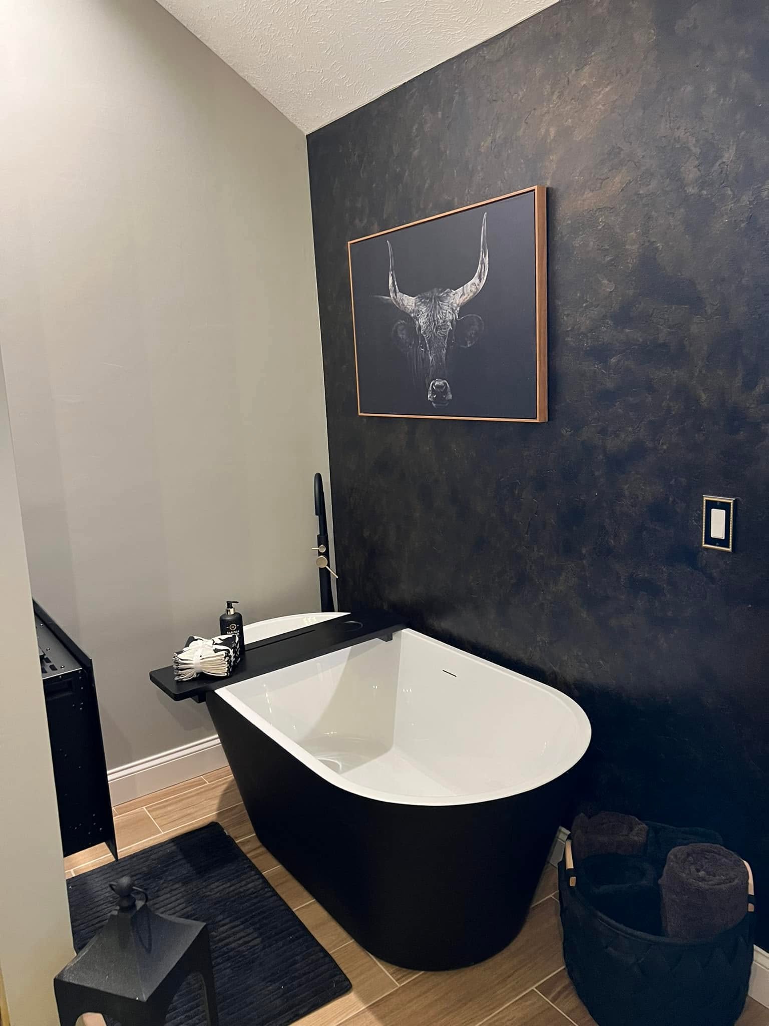 Black freestanding tub and tiled accent wall in a Bloomington, Illinois bathroom