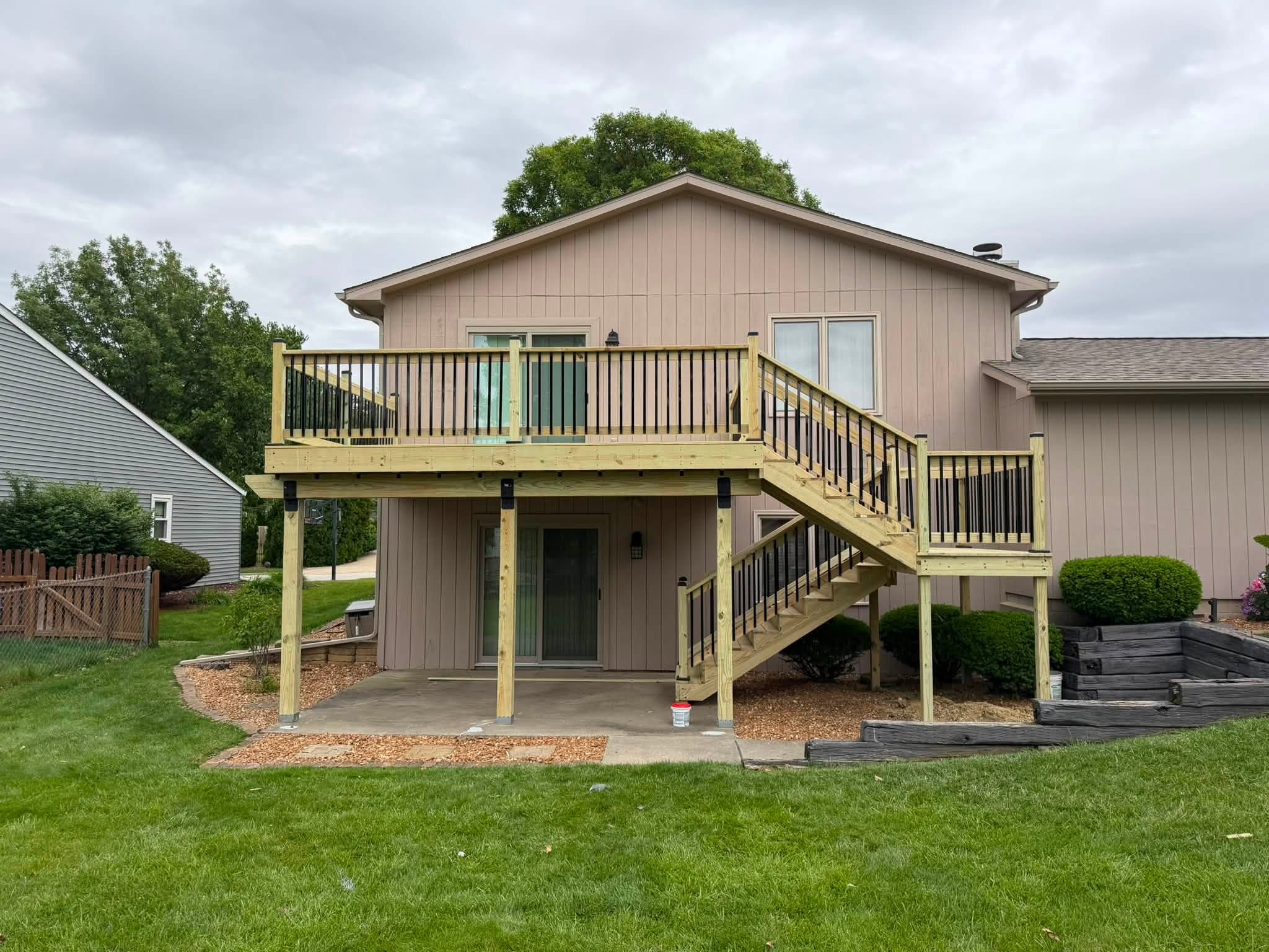Raised wood deck with dual staircases and black balusters in Bloomington, Illinois