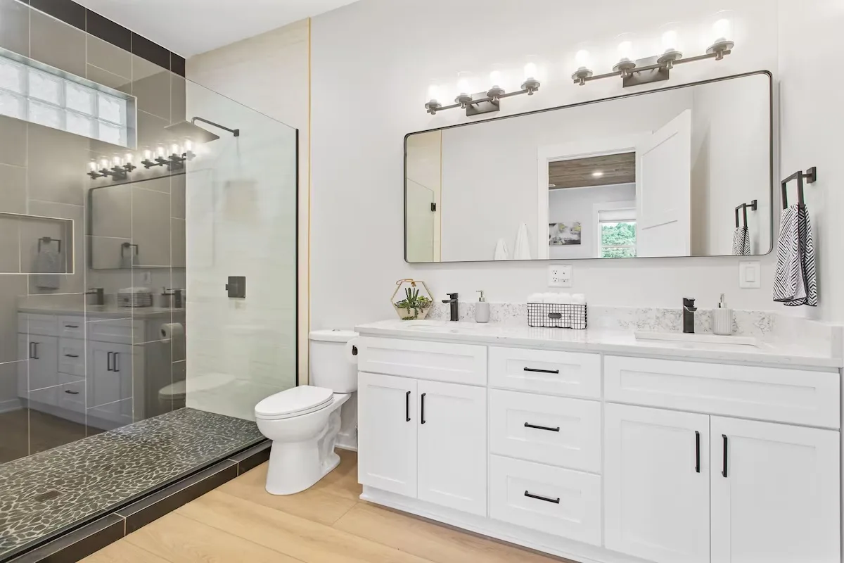 Bathroom remodel in Grand Rapids, Michigan with a glass walk-in shower, white double vanity and matte black fixtures