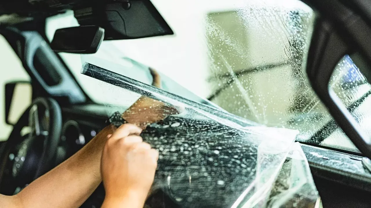Installer applying window tint film to a vehicle windshield