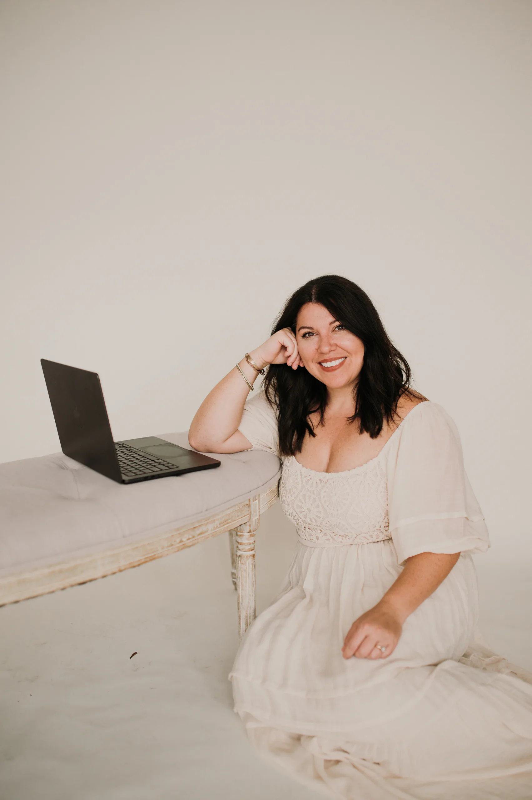 Woman sitting beside an open laptop in a bright minimalist studio. — how to drive more traffic to your website Woman sitting beside an open laptop in a bright minimalist studio. — how to drive more traffic to your website