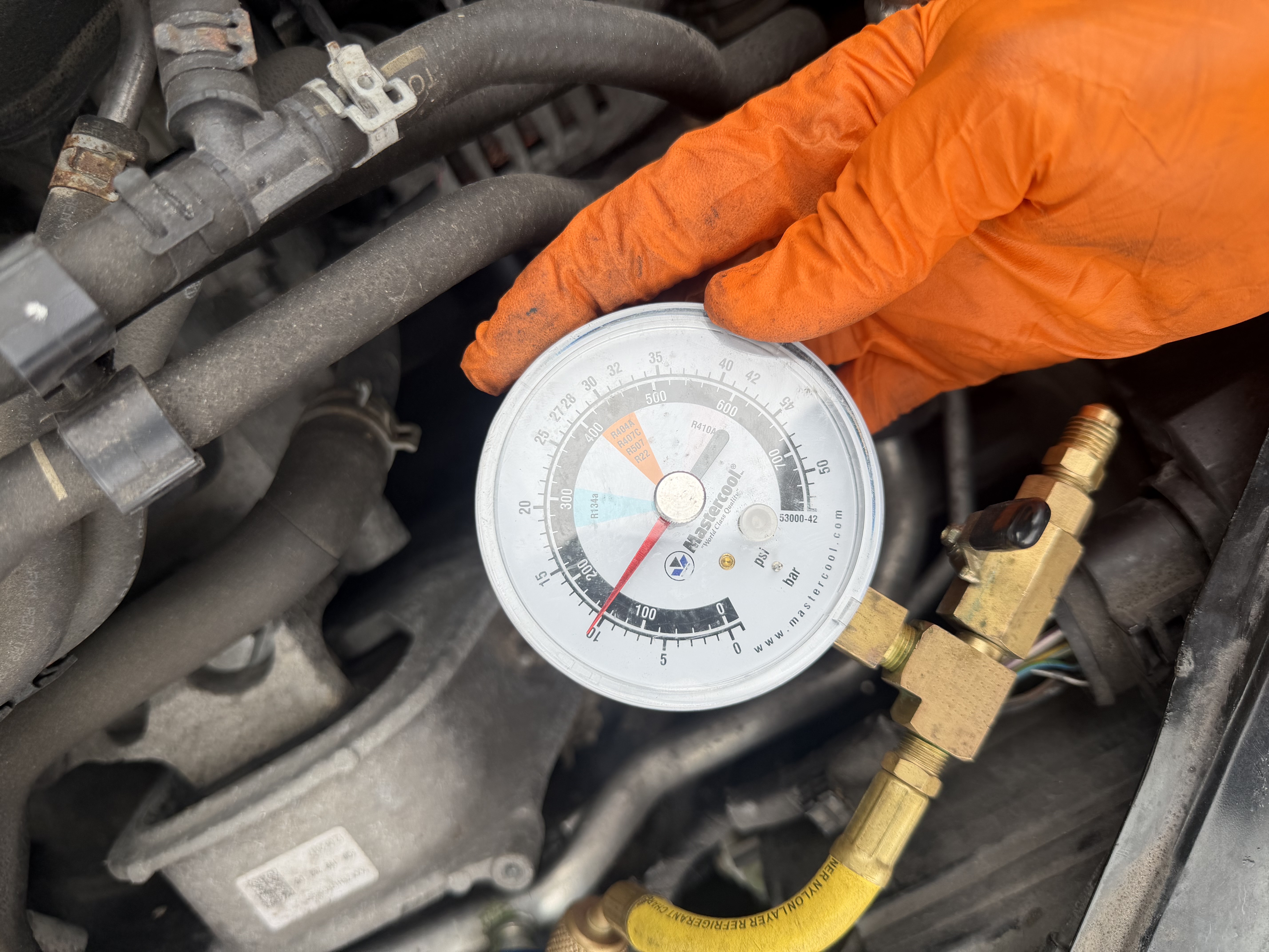 Mastercool AC pressure gauge connected to a vehicle air conditioning service port at Shaw's Service Station