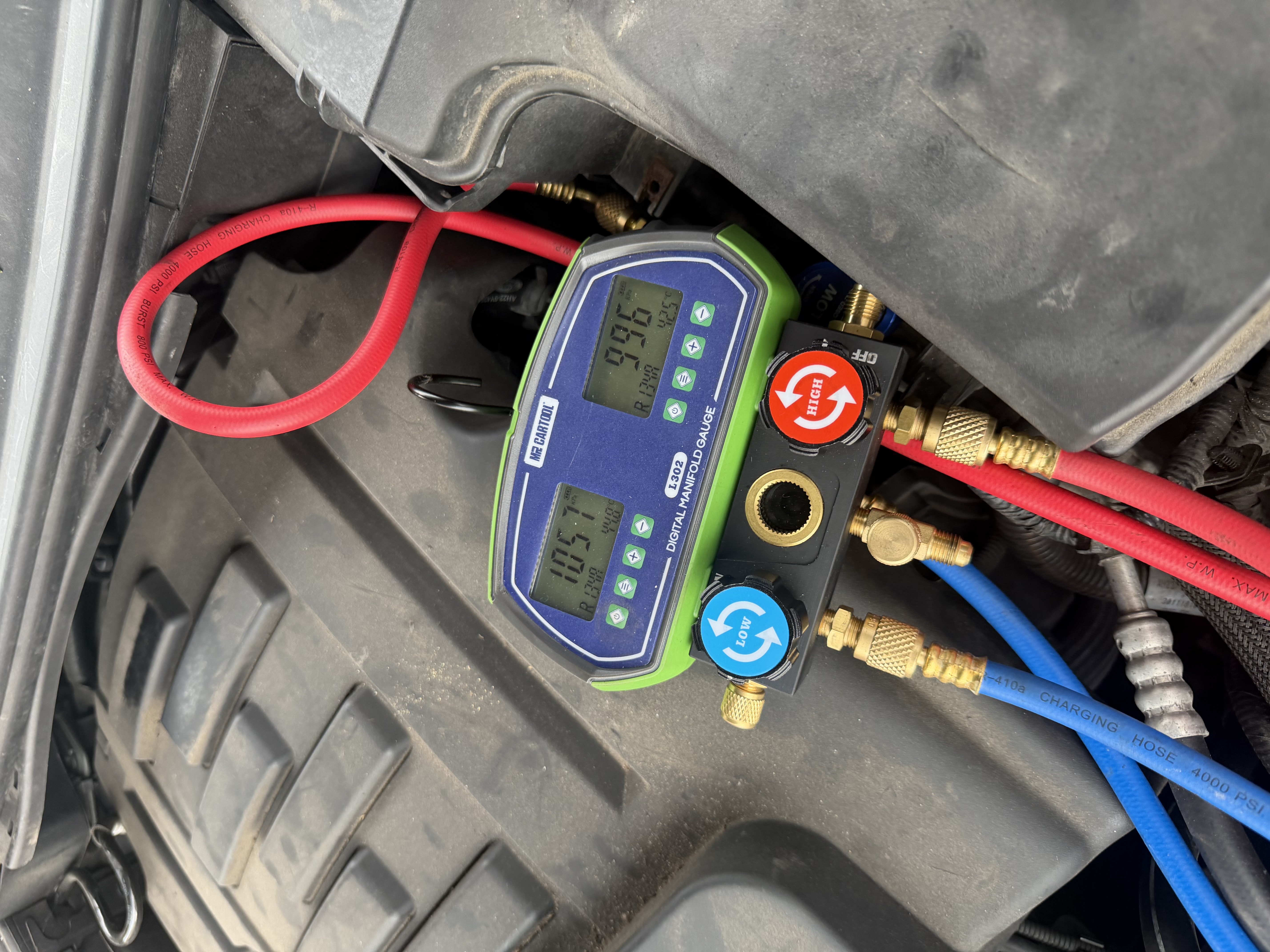 Digital manifold gauge showing air conditioning system pressure readings during an AC service at Shaw's Service Station