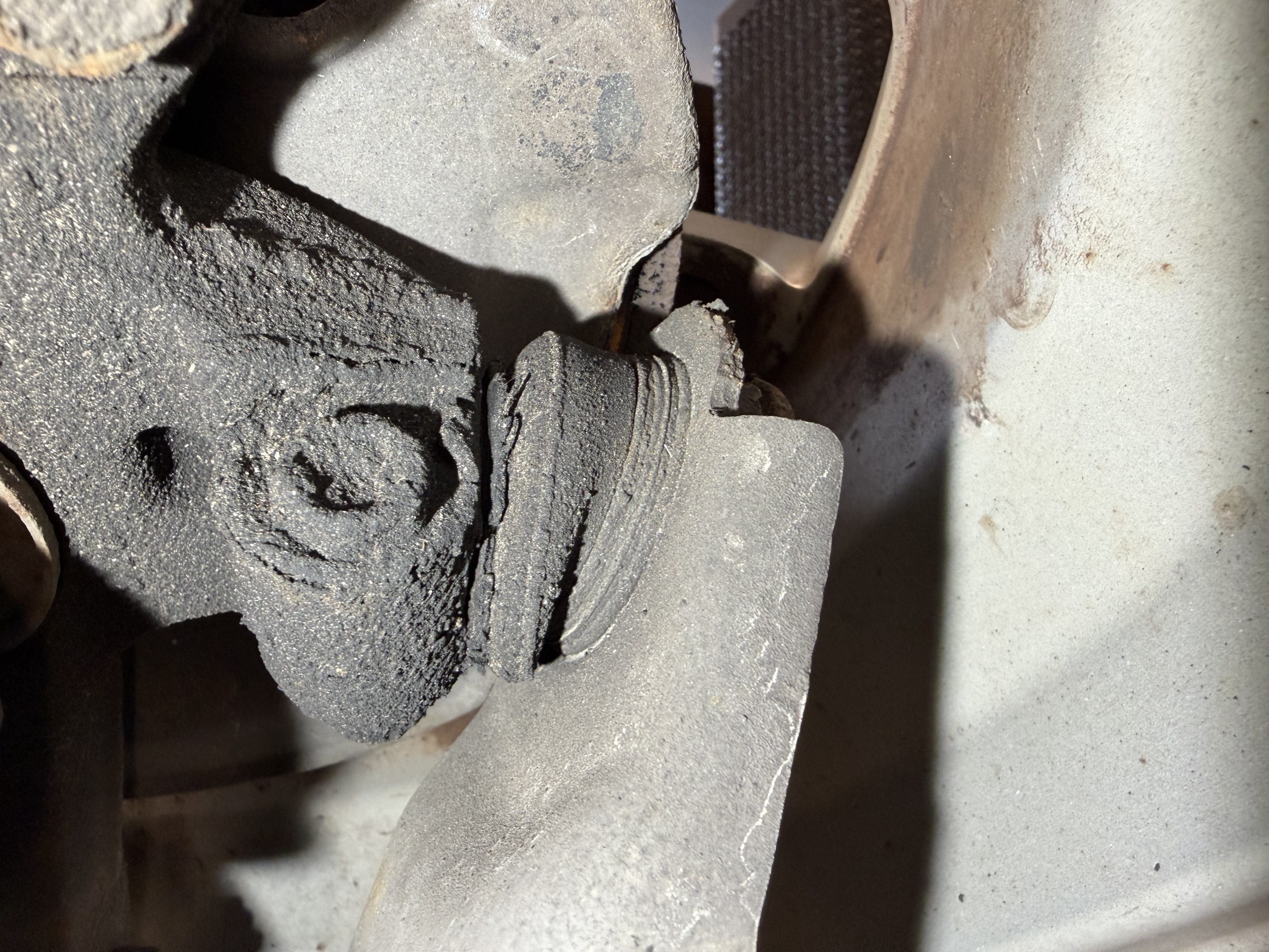 Deteriorated and grime-coated suspension control arm bushing in position on the vehicle at Shaw's Service Station
