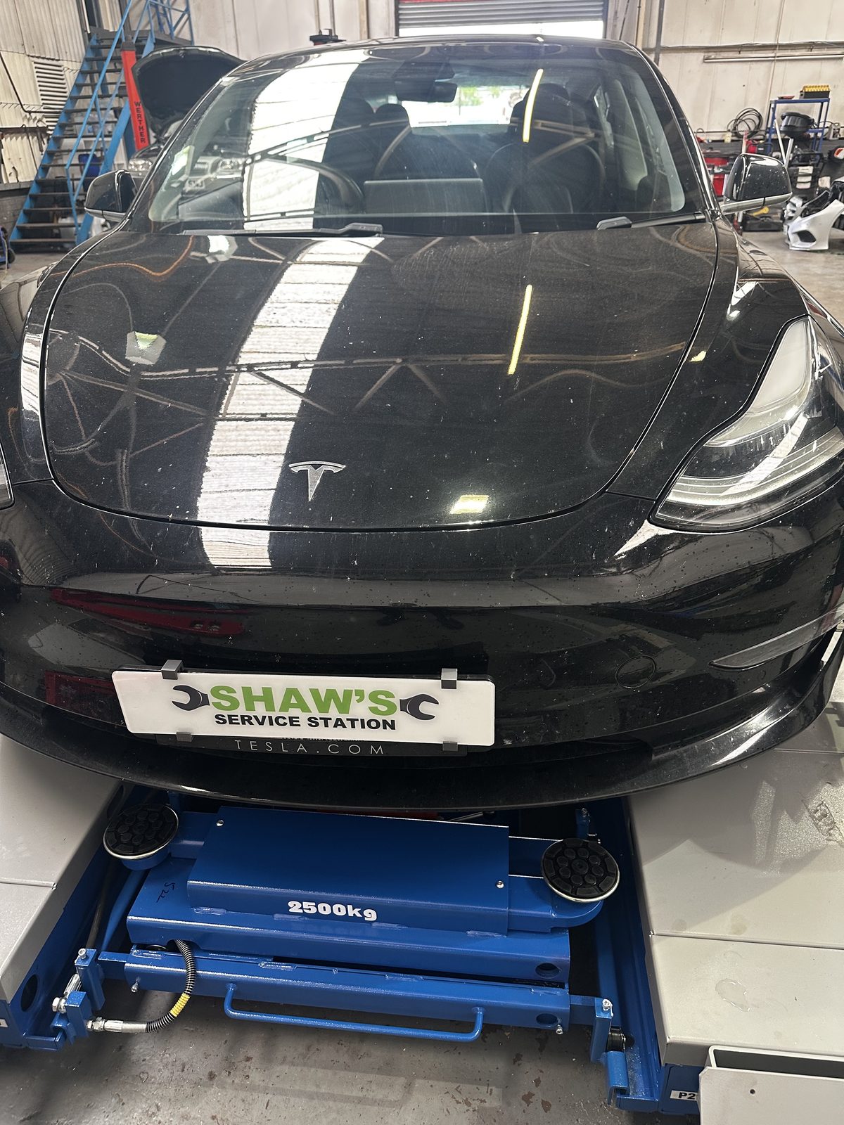 A black Tesla on a ramp in the Shaw’s Service Station workshop