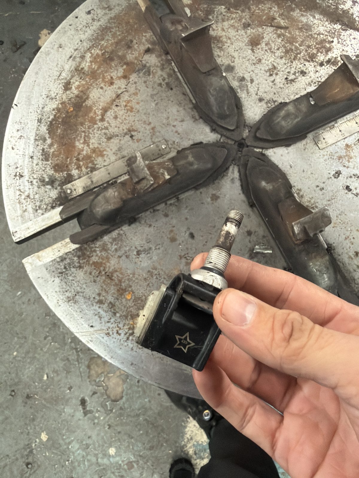 A hand holding a tyre pressure sensor with its metal valve stem