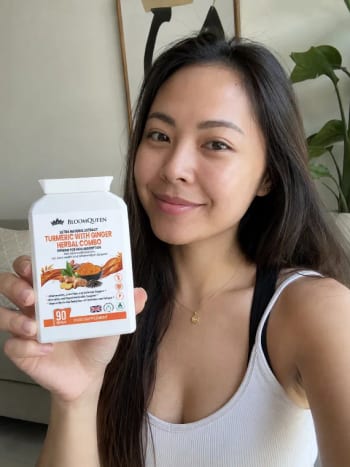 A woman holding a bottle of BloomQueen Turmeric at home
