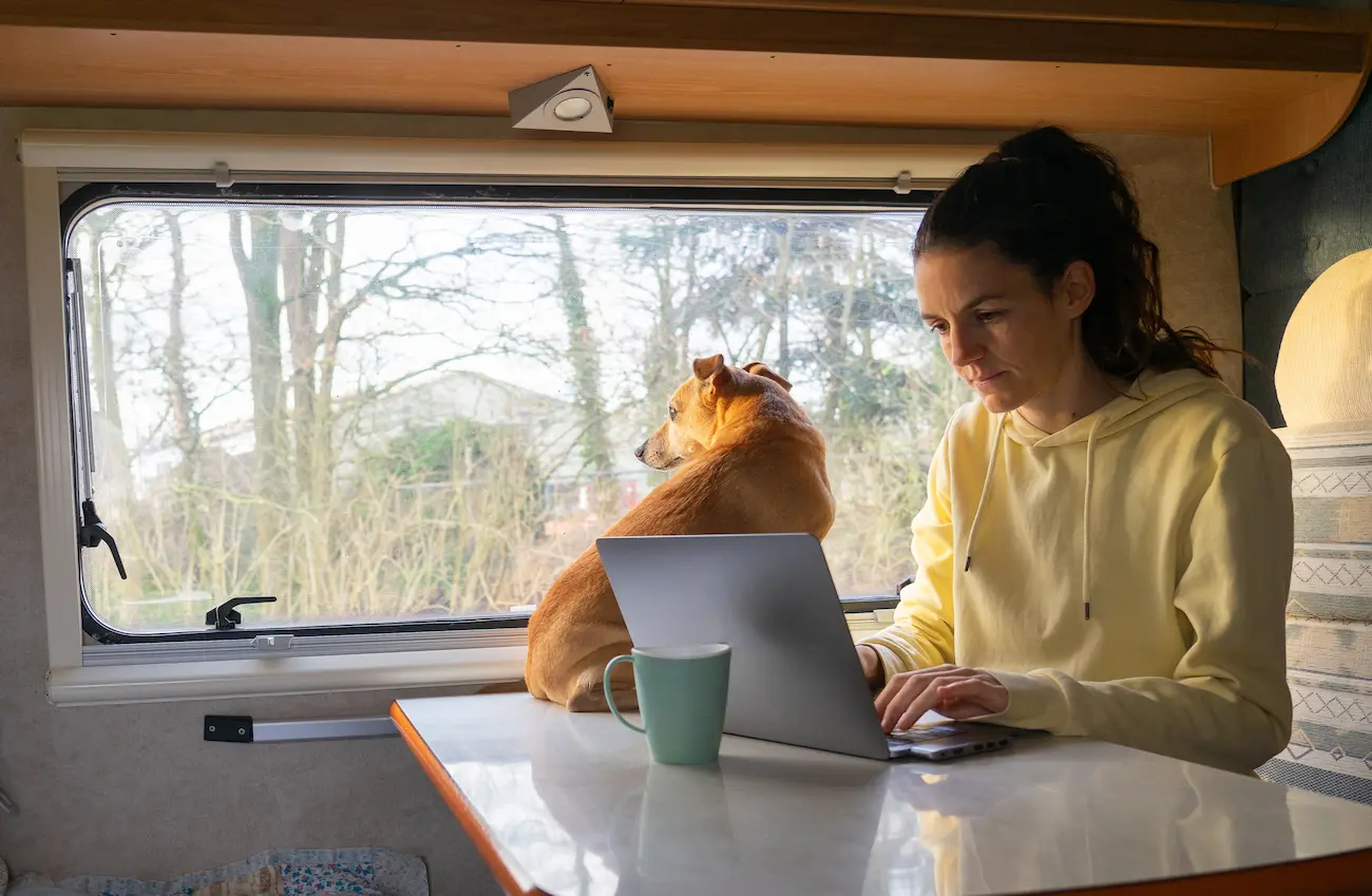 Digital nomad working from a compact RV workspace with a laptop and monitor