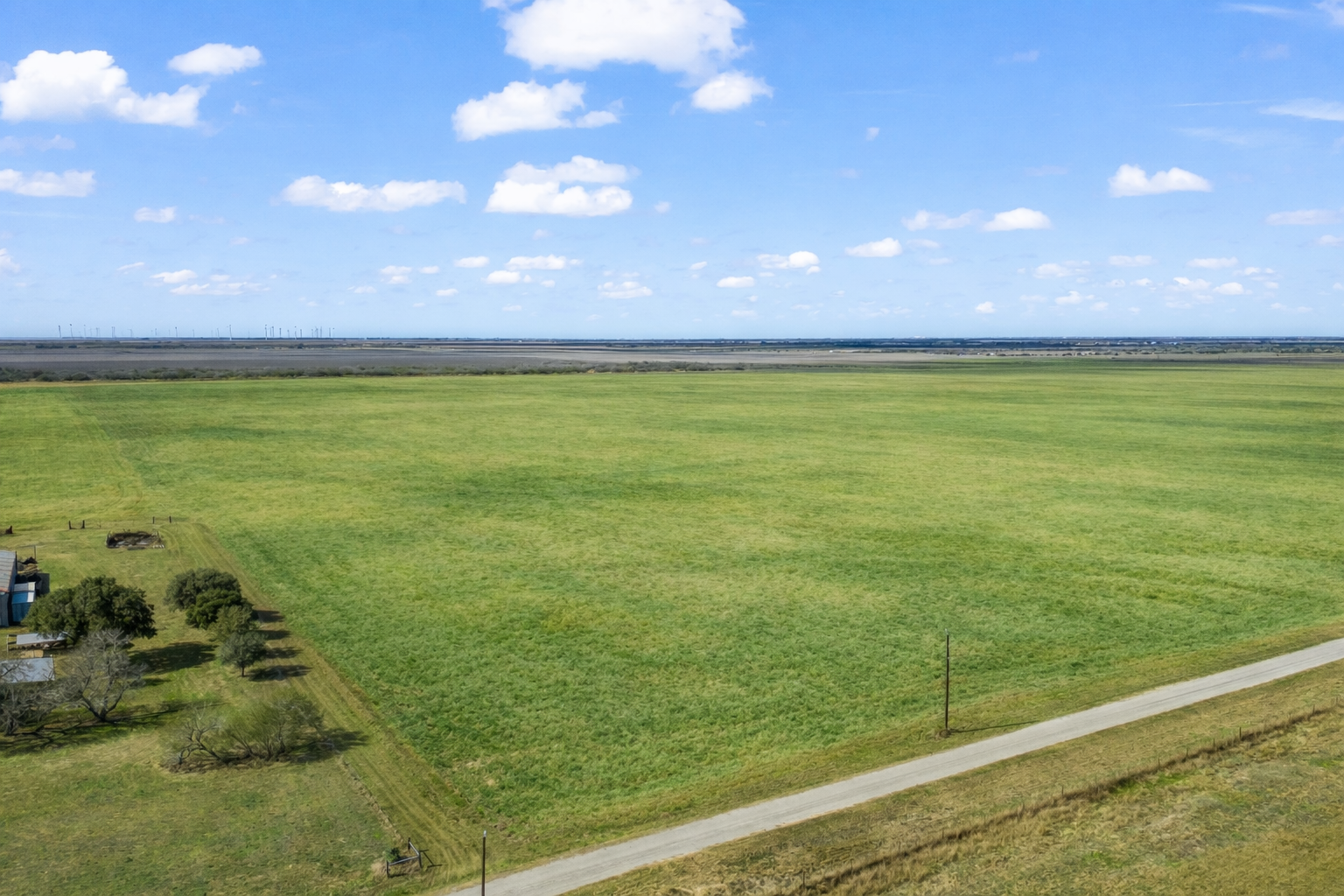 Aerial view of a green field with a tree line beside a road at Victory Estates near Sinton, Texas Aerial view of a green field with a tree line beside a road at Victory Estates near Sinton, Texas