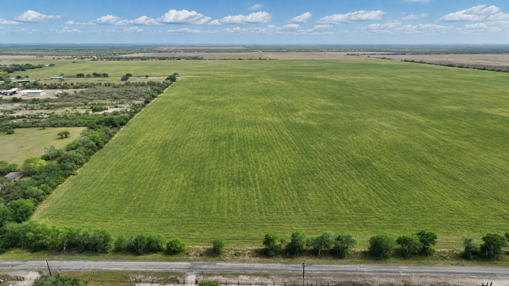 Aerial view of open green acreage beside a paved road at Victory Ranch near Orange Grove, Texas