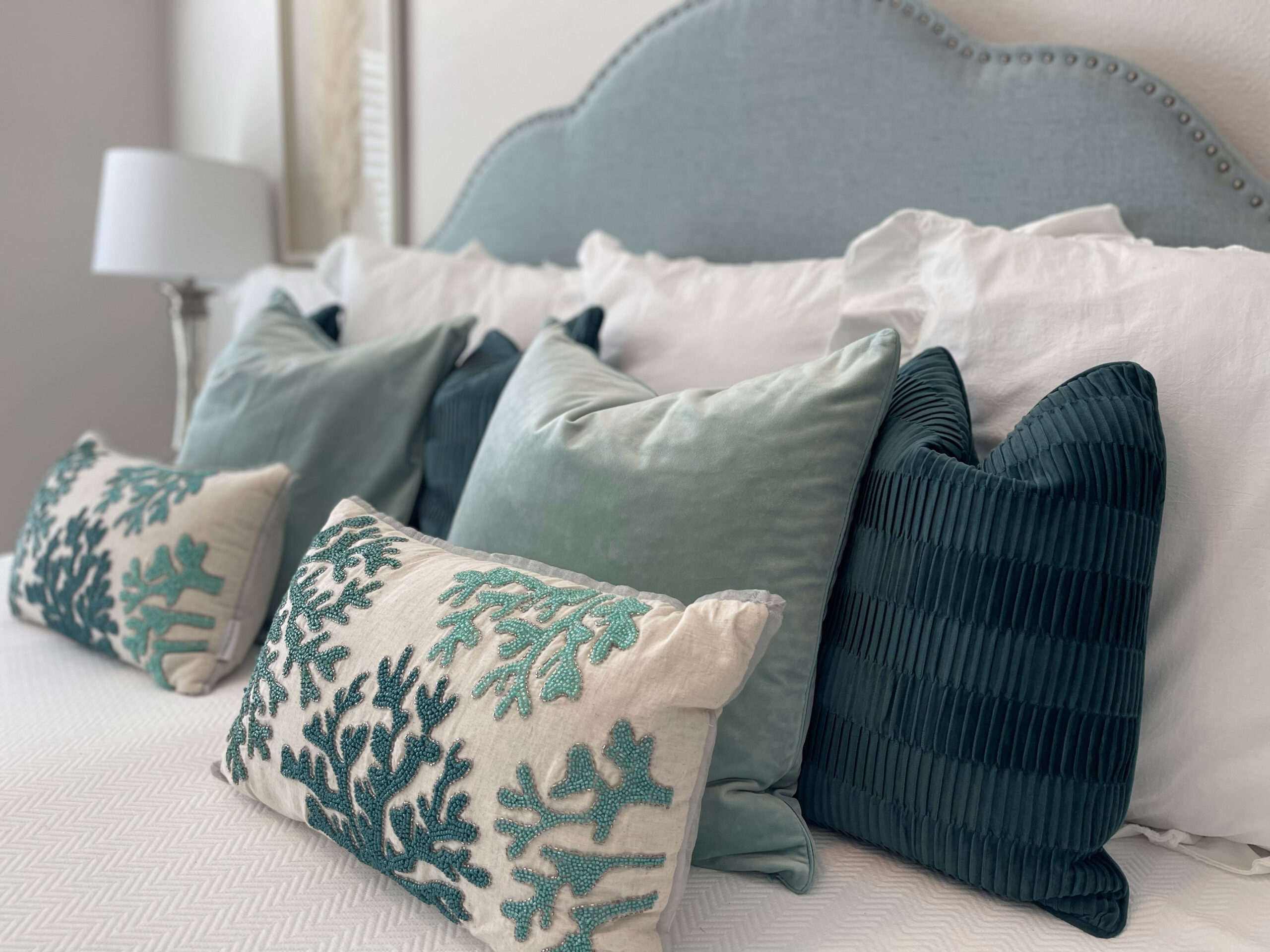 Coastal-styled throw pillows on a bed
