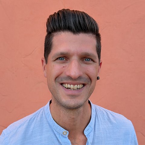 Porträt von Frank Kraeh, lachend vor einer orangen Wand
