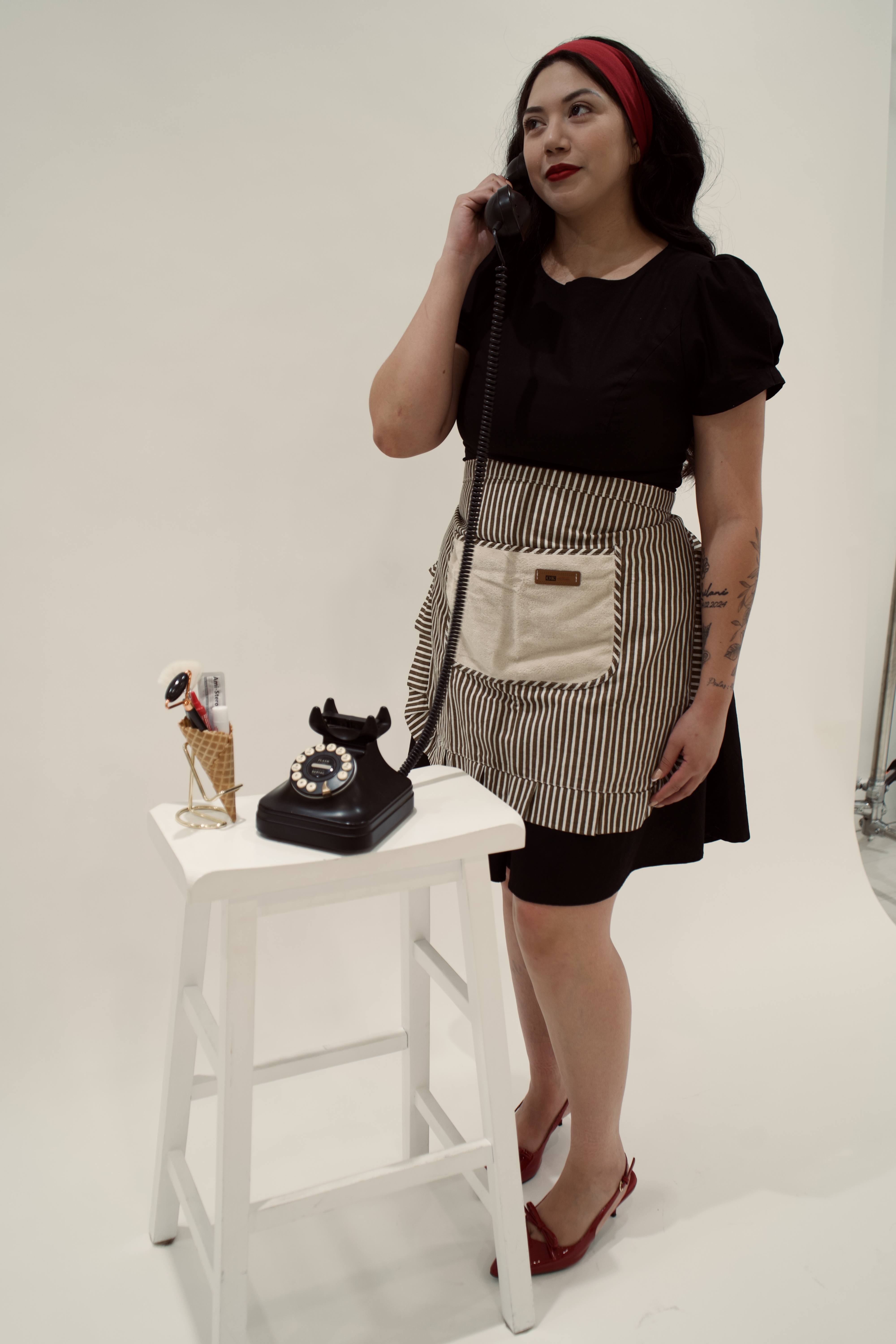 Bianca standing beside a vintage phone and a cone filled with skincare tools