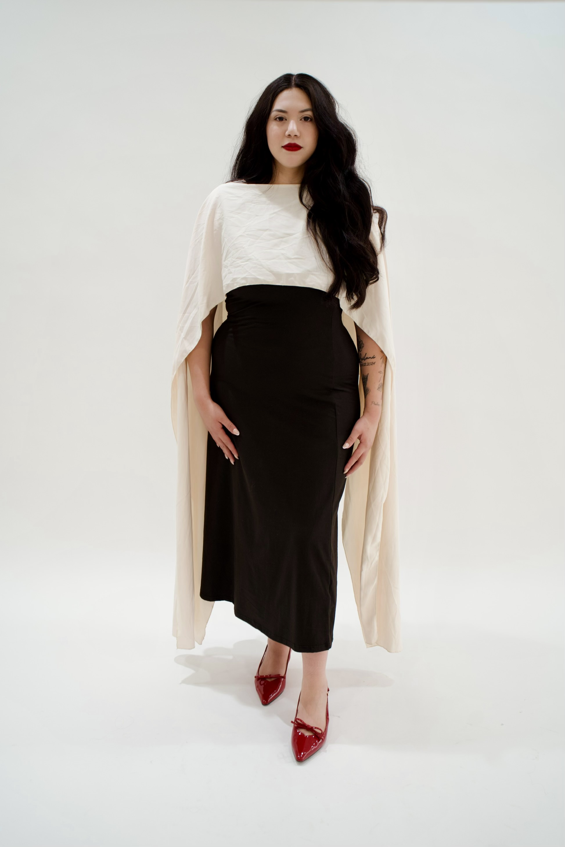 Bianca in a black dress with a flowing cream wrap and burgundy heels