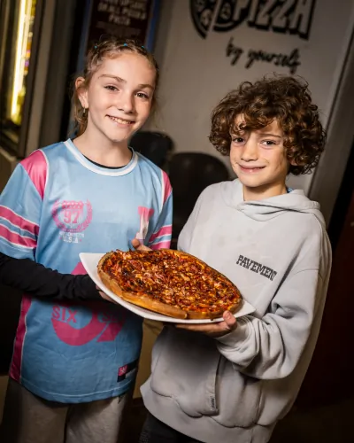 Two kids holding a pizza at a birthday party