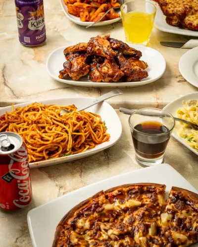 Overhead view of wings, spaghetti and pizza spread across a table