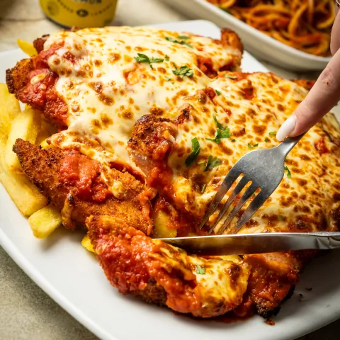 Chicken parmigiana with melted cheese and chips