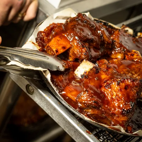 Close-up of glazed BBQ pork ribs with tongs