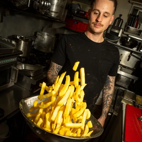 Chef holding a large pan of golden hot chips